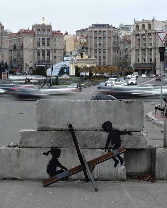 street art depicting an anti-tank hedgehog as a seesaw where children are playing