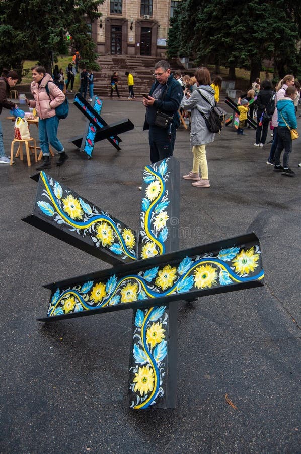 Hedgehogs (anti-tank devices made from 3 steel beams welded together) with blue and yellow flowers on them.