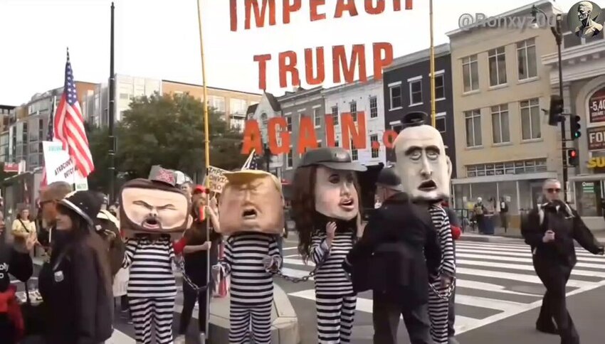 At a No Kings protest, caricatured people in jail stripes and paper-maiche heads of Trump, Vance, Kristi Noem, and Stephen Miller.