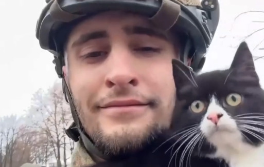 A Ukrainian soldier with a small black and white cat.